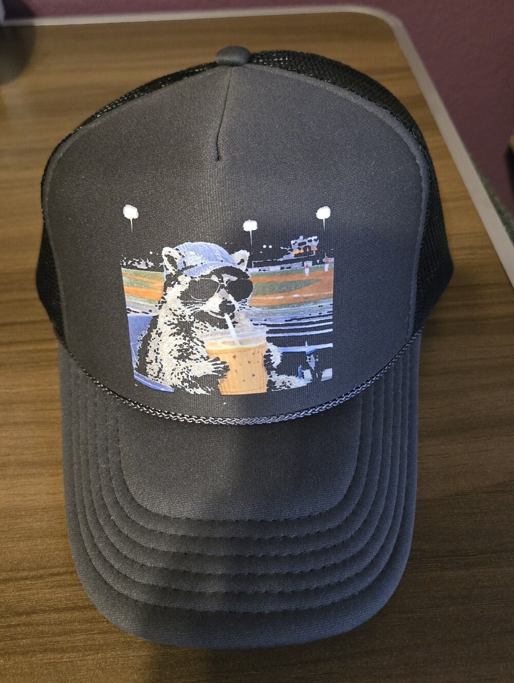 mesh trucker hat featuring a graphic patch of a raccoon wearing sunglasses